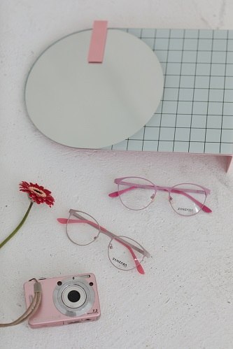 Damskie okulary korekcyjne Zanzara Eyewear w kolorze różowym obok aparat Instax